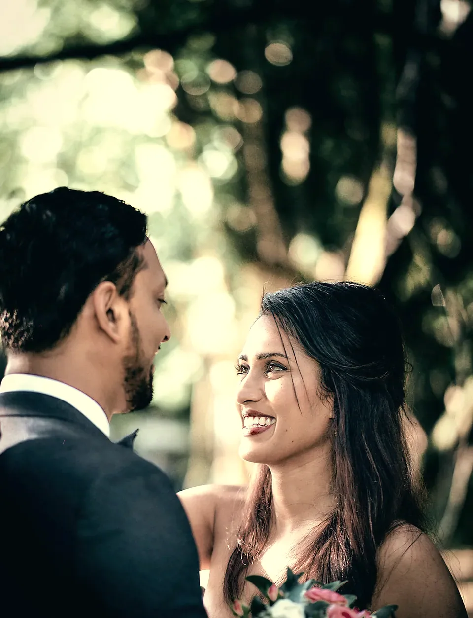 Anu smiling up at Ramith under the trees